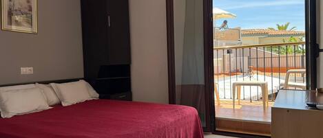 Un dormitorio con cama, armario, televisor y balcón con vistas.