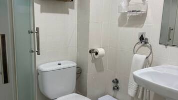 A bathroom with a toilet, a sink, a shower, and a towel rack.