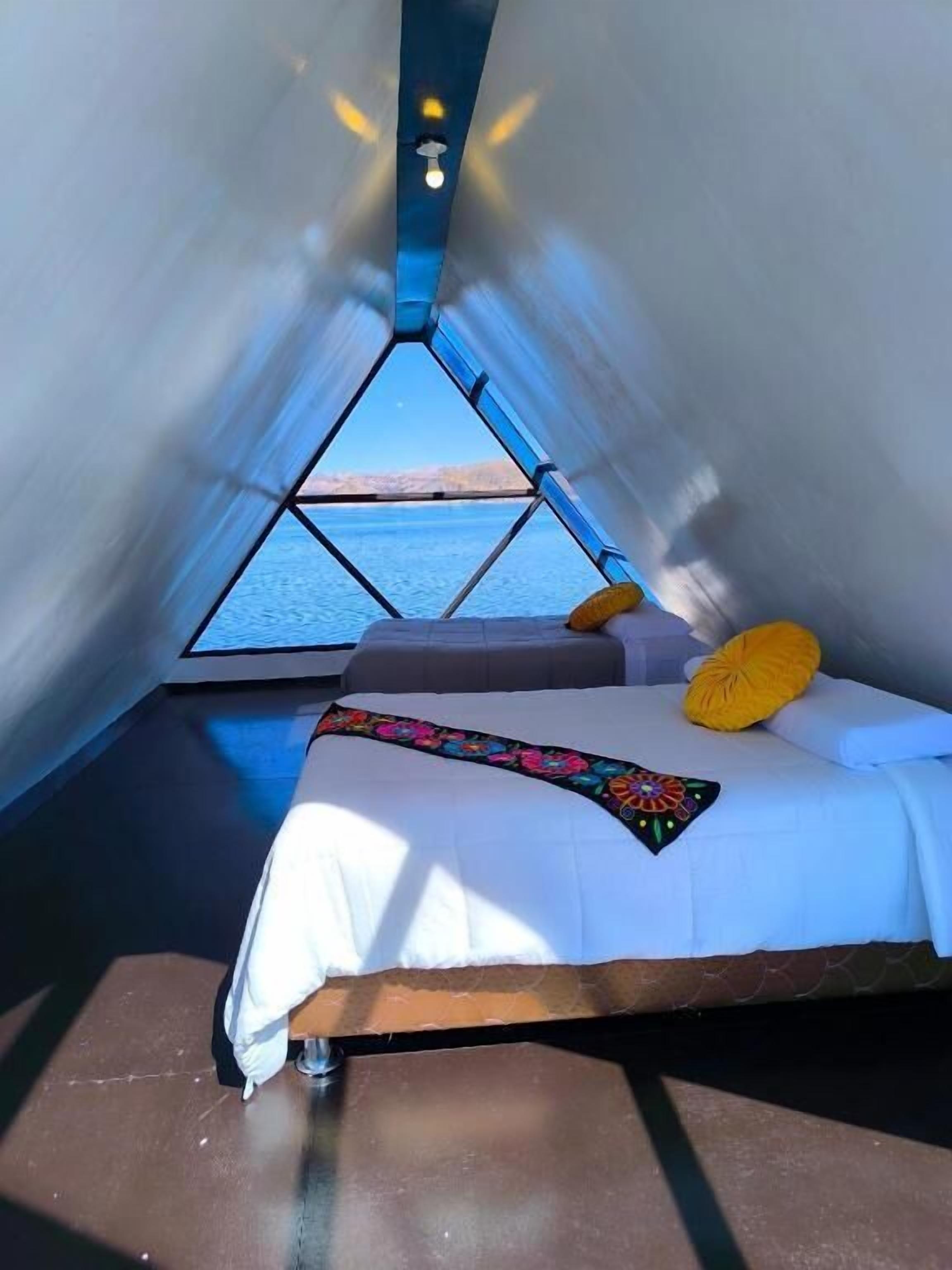 A room with a bed, pillows, and a view of the water.