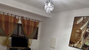 Ein modernes Wohnzimmer mit einer Couch, einem Couchtisch, einem Fernseher und einem dekorativen Buddha-Gemälde.