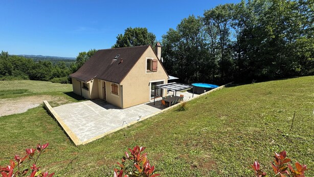 Ein Haus mit Terrasse, Swimmingpool und einem Rasen.