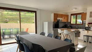 Eine moderne Küche mit Essbereich, großen Fenstern und Blick auf den Garten.