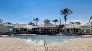 A swimming pool with lounge chairs and umbrellas, surrounded by buildings with a central dome structure.