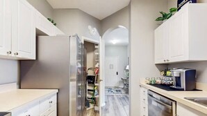A modern kitchen with stainless steel appliances, white cabinetry, and a central island.