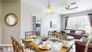 A dining area with a glass table set for four, surrounded by wooden chairs.