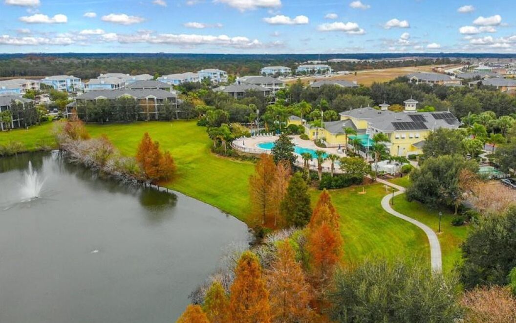 A golf course with a pond, surrounded by residential buildings and a swimming pool area.