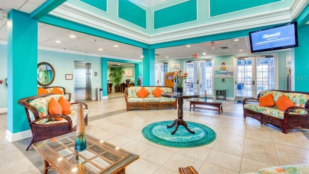 A spacious lobby with teal walls, wicker furniture, and a central table. - Bahama Bay Spacious 3BR Condo + Resort Amenities (Davenport)