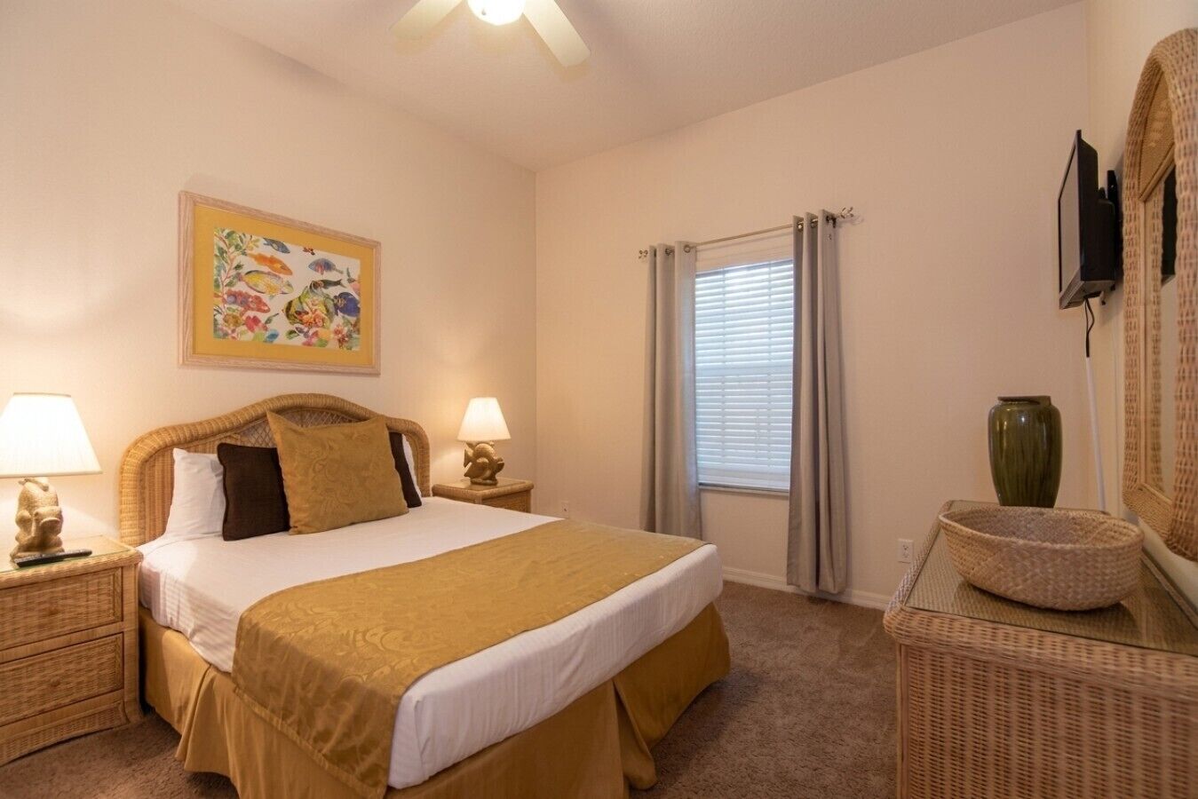 A hotel room with a bed, two bedside tables, a lamp, a painting, a window with curtains, a vase, and a television.