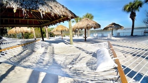 A hammock set up on a sandy beach with a thatched-roof structure in the background. - Bahama Bay Spacious 3BR Condo + Resort Amenities (Davenport)