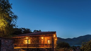 A stone building with a balcony, a wooden door, and a view of the mountains. - Taygetos Relaxing Cottage (Poliani)