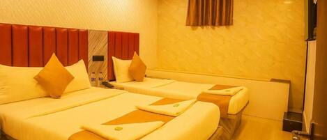 A hotel room with two beds, a wooden headboard, a flat-screen TV, and a small table.