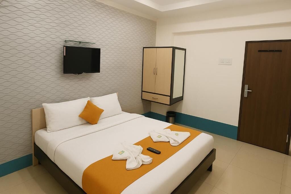 Quarto de hotel com cama, televisão presa na parede, guarda-roupa e porta.