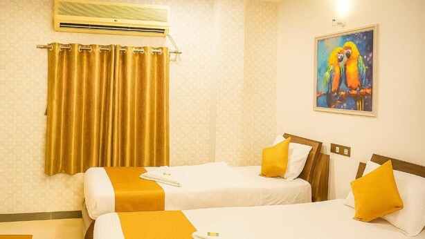 A hotel room with two beds, a painting of parrots, and a curtain. - Hotel Blue Sunrise near Mumbai Airport (Mumbai)