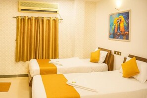 Een hotelkamer met twee bedden, een schilderij van papegaaien en een gordijn.