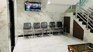 A lobby with marble flooring, a TV mounted on the wall, a staircase, and a row of chairs. - Hotel Blue Sunrise near Mumbai Airport (Mumbai)