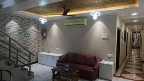 A lobby with a staircase, a red leather sofa, a wooden coffee table, and a ceiling fan. - Hotel Blue Sunrise near Mumbai Airport (Mumbai)