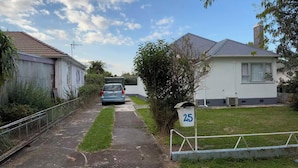A residential street with houses, a parked car, and a mailbox marked with the number 25. - 3 bedroom house (Rotorua)