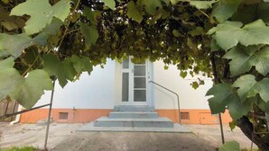 A building with a staircase leading to a door, surrounded by greenery. - 3 bedroom house (Rotorua)