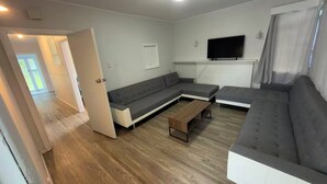 A living room with a sectional sofa, a coffee table, and a flat-screen TV mounted on the wall. - 3 bedroom house (Rotorua)