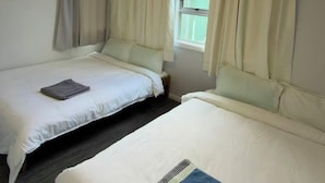 A hotel room with two beds, a window with curtains, and a ceiling light. - 3 bedroom house (Rotorua)