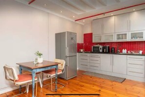 Eine kompakte Küche mit Kühlschrank, Mikrowelle und einer roten Fliesenfassade.