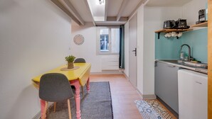 A compact kitchen with a sink, a coffee machine, and a refrigerator. There is a dining area with a yellow table and chairs. - L'Ô en Couleur - Au coeur de Bordeaux (Bordeaux)