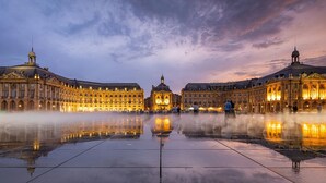 A grand historic building with a central dome and symmetrical wings, a spacious reflective plaza, and a clear sky. - L'Ô en Couleur - Au coeur de Bordeaux (Bordeaux)