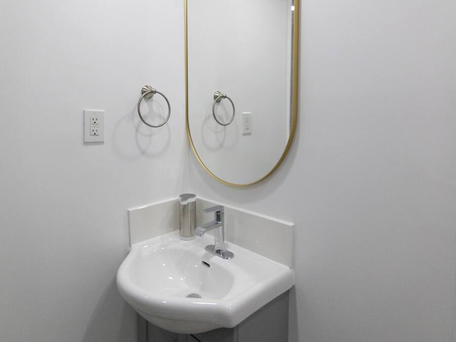 A bathroom with a white sink, a gold-framed mirror, and a towel ring.
