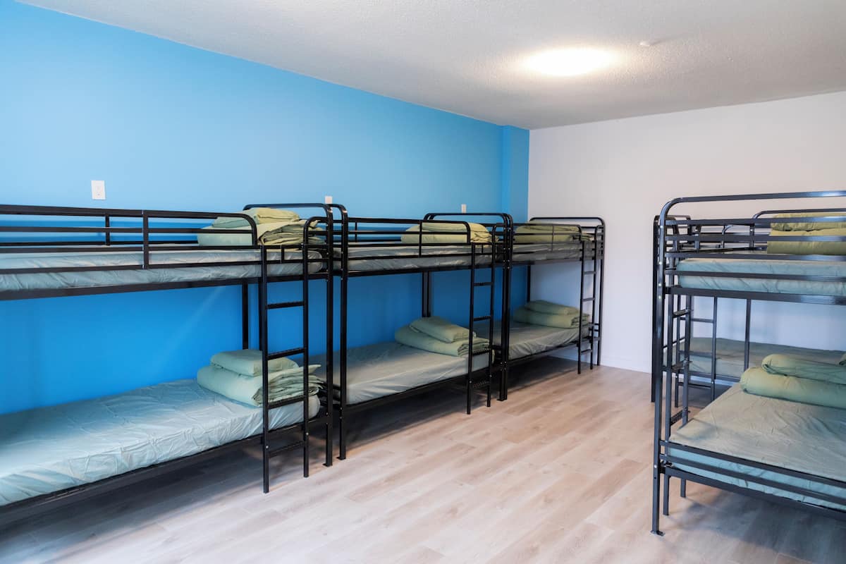 Une chambre de dortoir avec des lits superposés, un plancher en bois et des murs bleus.