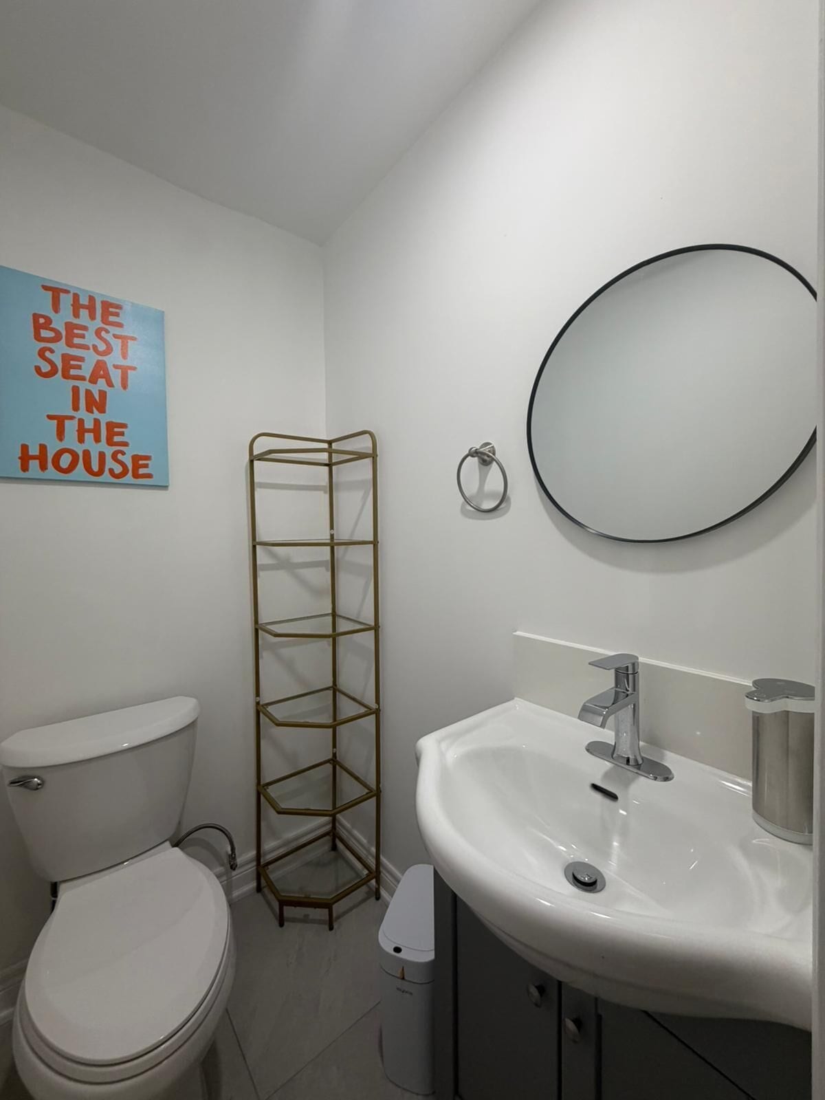 Een badkamer met toilet, wastafel, spiegel, handdoekhouder en een decoratief bordje.