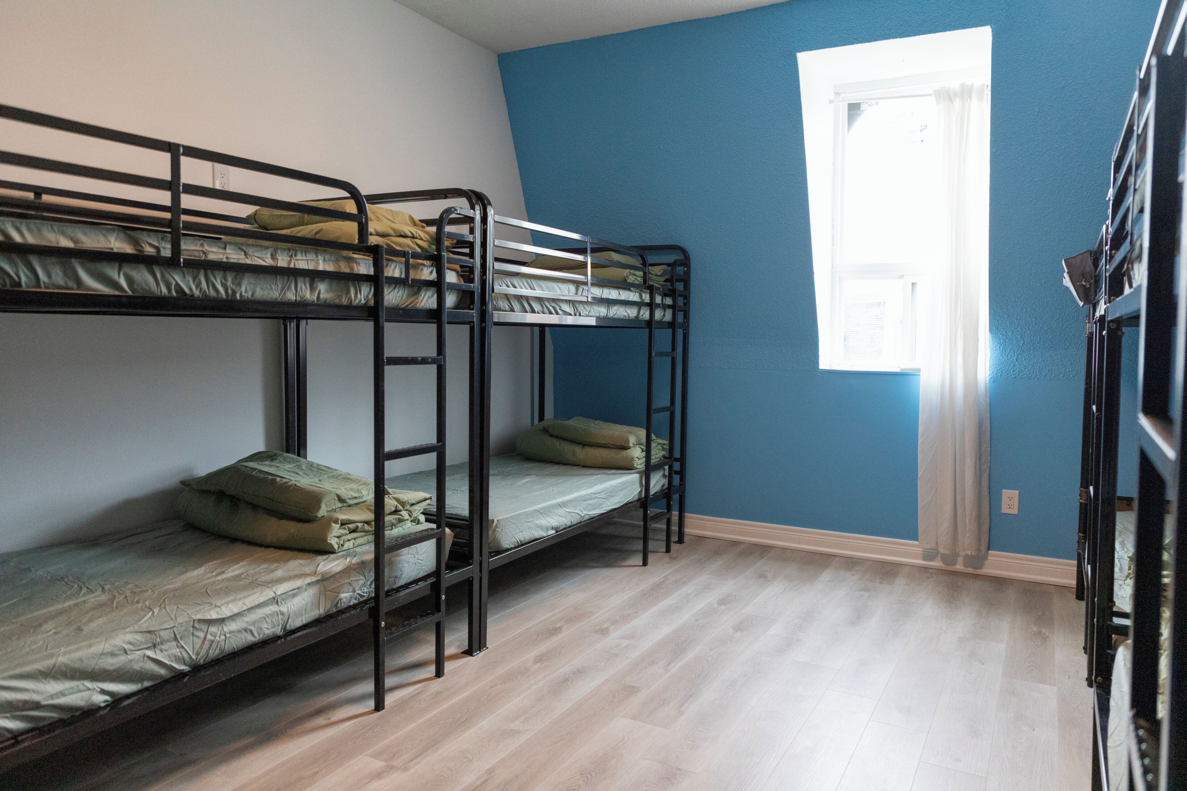 Una habitación con literas, una ventana y suelo de madera.