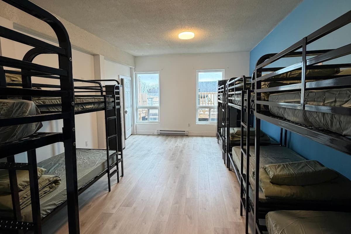 Une chambre de dortoir avec des lits superposés, un plancher en bois et un luminaire au plafond.