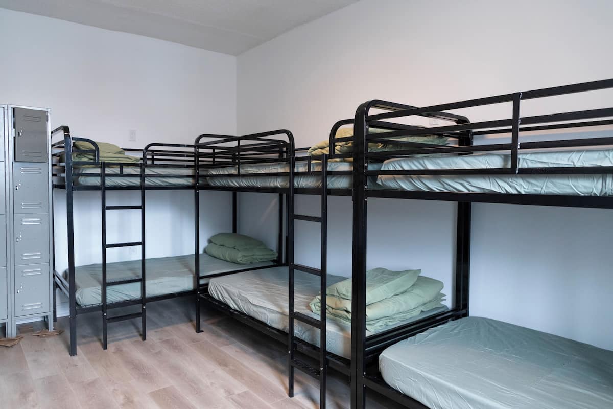Une chambre avec un lit superposé, une armoire en métal et un plancher en bois.