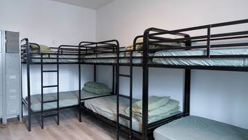 A bunk bed room with a metal wardrobe and a wooden floor.