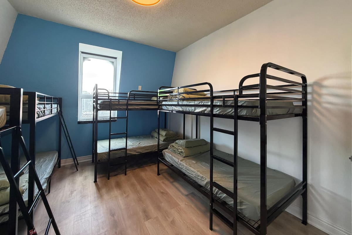 Une chambre avec des lits superposés, une fenêtre et un luminaire au plafond.