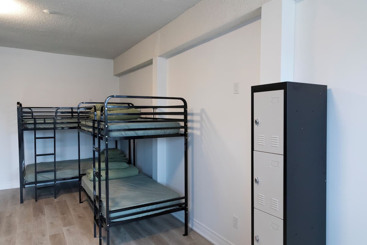 Une chambre avec un lit superposé, une armoire et un interrupteur sur le mur.