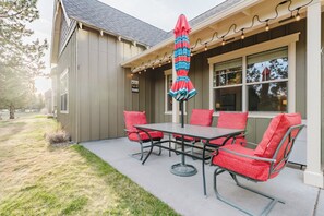 Een terras buiten met een tafel, stoelen, een hangende parasol en een bord met een vermelding van Seattle.