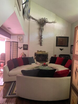 A living room with a curved sofa, a fireplace, and a decorative tree branch on the wall.