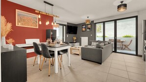 A modern living room with a dining area, a gray sofa, and a kitchen in the background. - L'Harona - Proche de la gare et du métro (Toulouse)