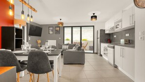 A modern kitchen with white cabinets, a dining area with grey chairs, and a large window. - L'Harona - Proche de la gare et du métro (Toulouse)