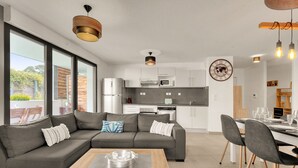 A modern living room with a sectional sofa, a wooden coffee table, and a dining area with chairs and a table set for a meal. - L'Harona - Proche de la gare et du métro (Toulouse)