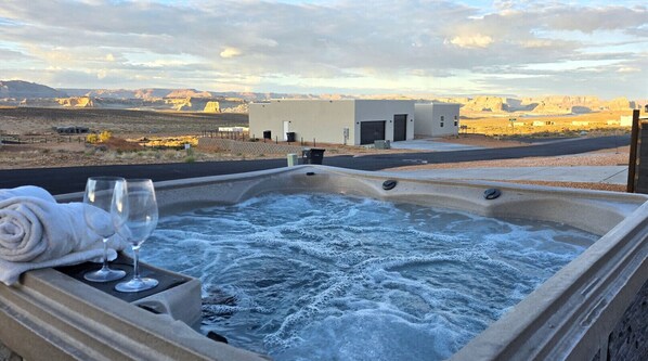Un jacuzzi con una toalla y copas de vino, con el paisaje desértico y un edificio de fondo.