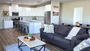Una cocina moderna con armarios blancos, un refrigerador de acero inoxidable y una isla central con taburetes.