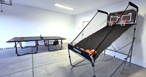 Una cancha de baloncesto con aro, una mesa de tenis de mesa y una silla.
