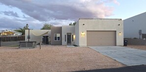 A modern two-story house with a garage, a patio with outdoor furniture, and a covered area.