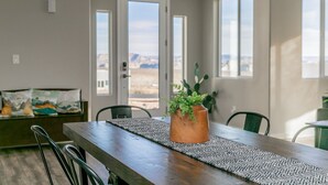 Un comedor con una mesa de madera, sillas, un tapete y una planta en maceta.