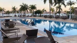 A swimming pool with lounge chairs and palm trees. - View 462 just for you! (Plano Piloto)