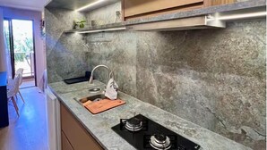 A kitchen with a granite countertop, a gas stove, a sink, and wooden cabinets. - View 462 just for you! (Plano Piloto)