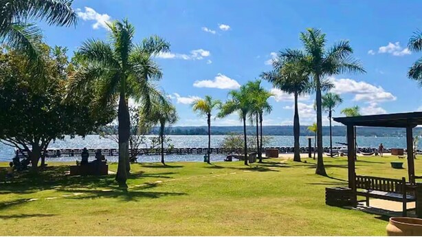 A park with palm trees, a grassy area, and a view of the water. - View 462 just for you! (Plano Piloto)