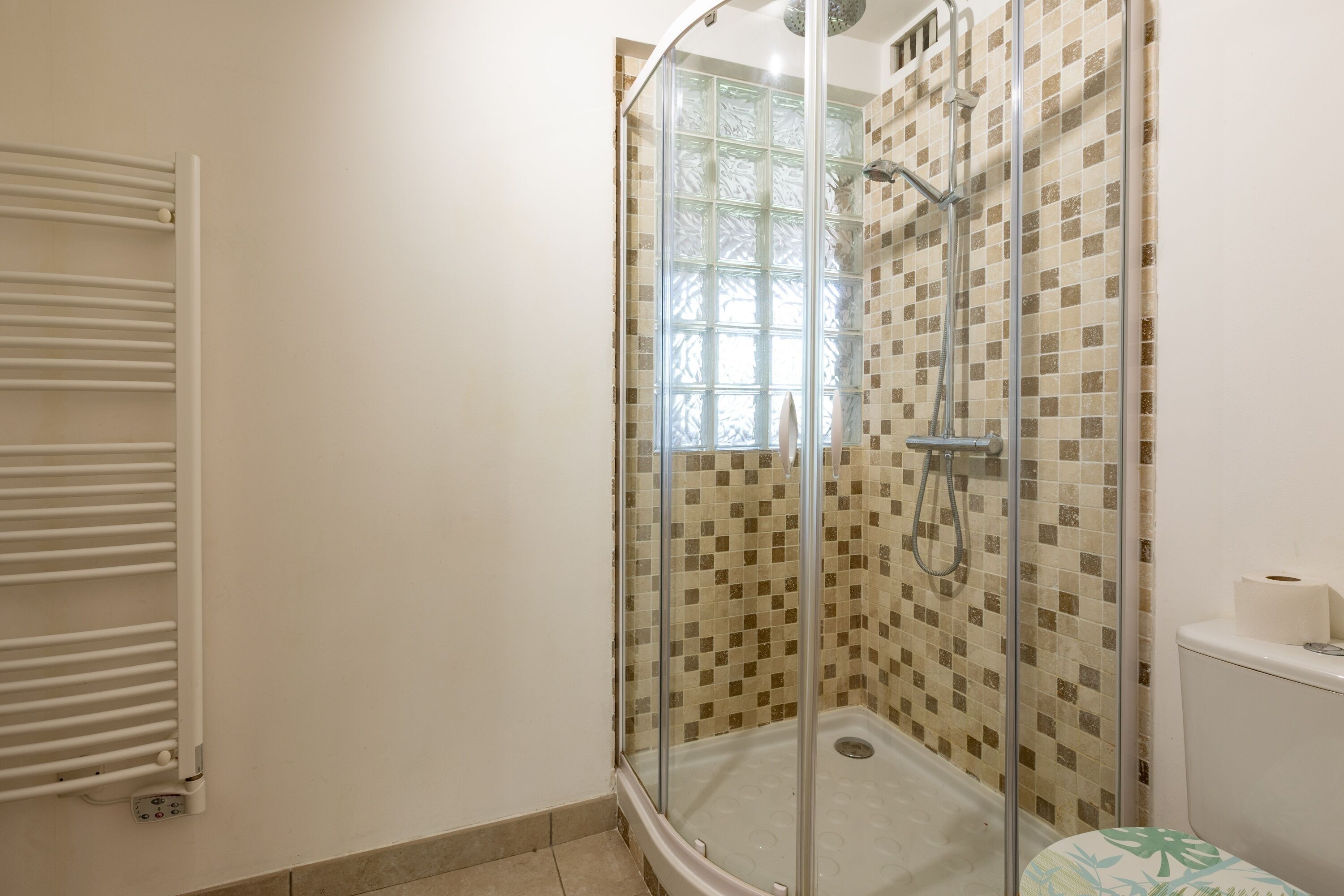 Une salle de bain avec une douche à parois de verre, des toilettes et un porte-serviettes.